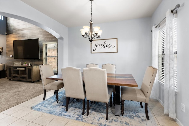dining area featuring a chandelier, light tile patterned floors, arched walkways, and baseboards