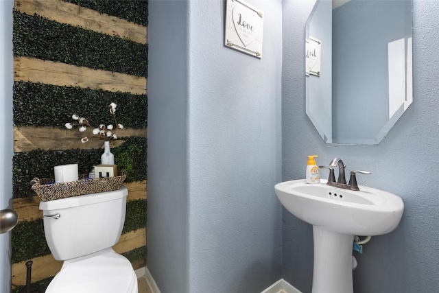 bathroom with toilet, baseboards, and a sink