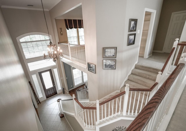 foyer entrance featuring a chandelier, stairway, a towering ceiling, and ornamental molding