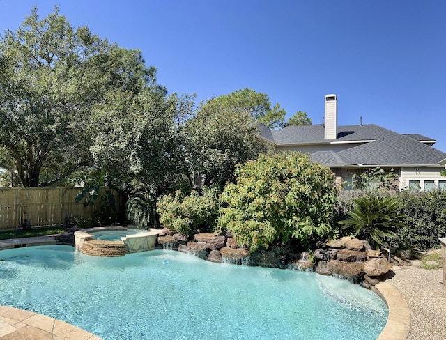 view of swimming pool with fence and a pool with connected hot tub