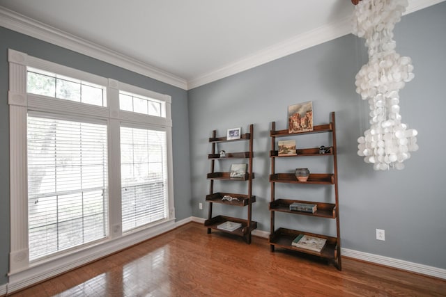empty room featuring baseboards, crown molding, and wood finished floors