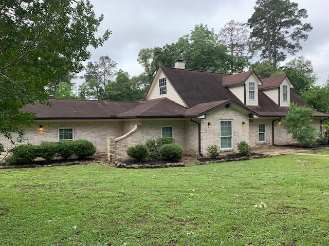 view of front of home featuring a front yard, a chimney, and stone siding