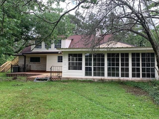 back of house with a sunroom, a yard, a wooden deck, and central AC
