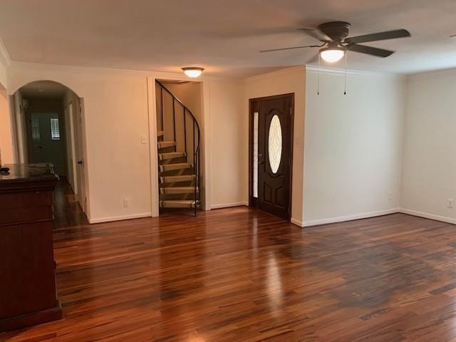 entrance foyer featuring arched walkways, a ceiling fan, crown molding, stairs, and wood finished floors