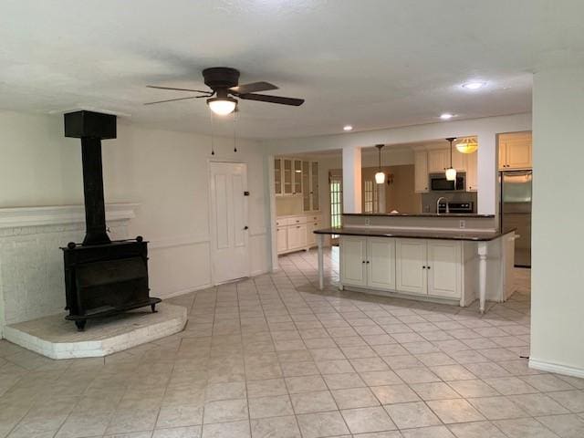 kitchen featuring appliances with stainless steel finishes, ceiling fan, dark countertops, recessed lighting, and a wood stove