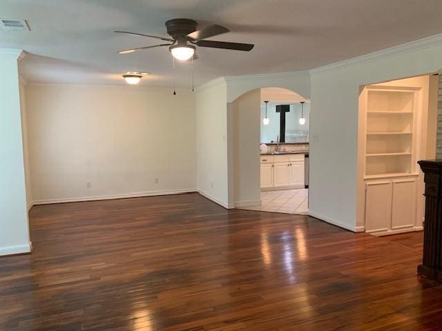 unfurnished living room with a ceiling fan, crown molding, wood finished floors, arched walkways, and baseboards