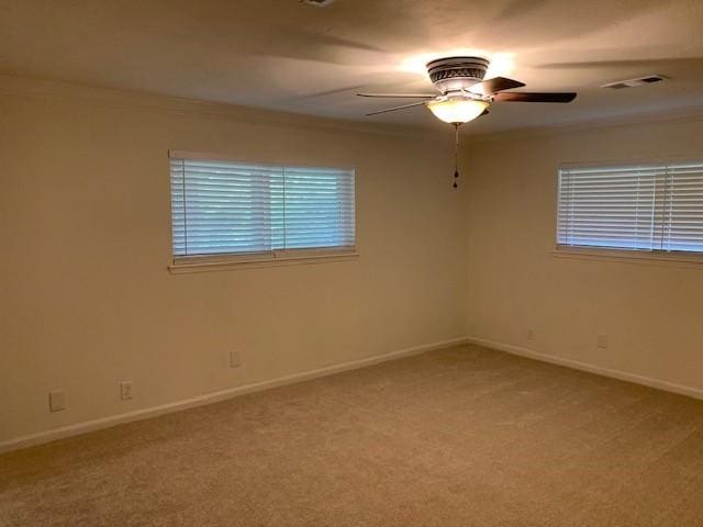 spare room with ceiling fan, light colored carpet, baseboards, and crown molding