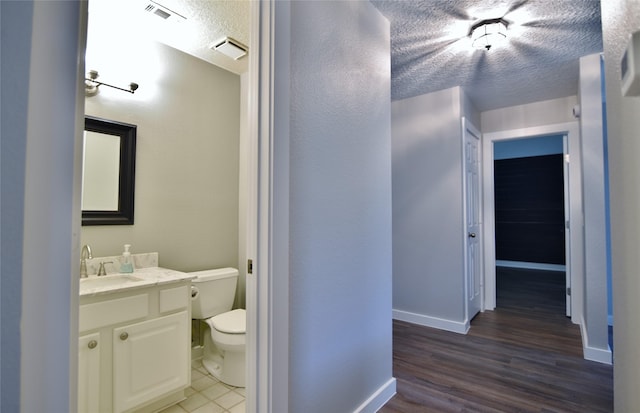 18411 Arrow Flint Cv, Houston, TX 77084 - bathroom with a textured ceiling, toilet, baseboards, vanity, and wood finished floors
