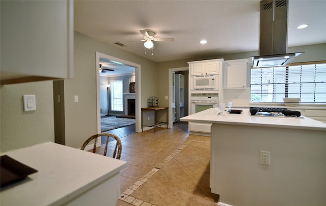 18411 Arrow Flint Cv, Houston, TX 77084 - kitchen with white appliances, a ceiling fan, island exhaust hood, light tile patterned flooring, and white cabinetry