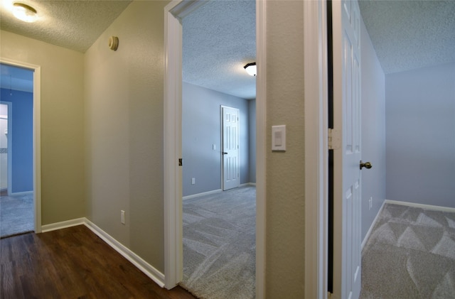 18411 Arrow Flint Cv, Houston, TX 77084 - hallway featuring a textured ceiling, dark colored carpet, baseboards, and dark wood-style flooring