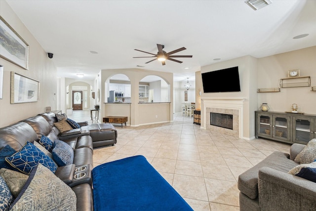 living area featuring arched walkways, ceiling fan, light tile patterned flooring, and baseboards