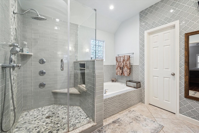 bathroom with a garden tub, a stall shower, tile patterned flooring, lofted ceiling, and baseboards