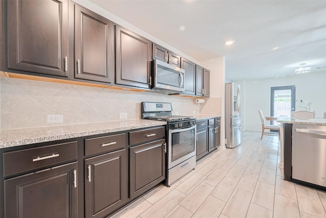 20864 Sheffield Park Dr, Porter, TX 77365 - kitchen featuring appliances with stainless steel finishes, backsplash, dark brown cabinetry, light stone countertops, and recessed lighting