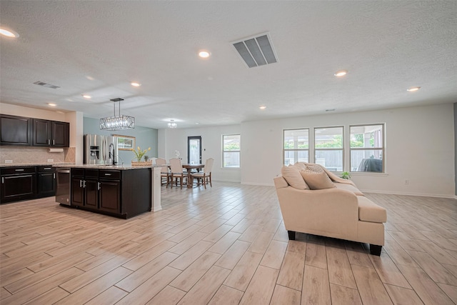 20864 Sheffield Park Dr, Porter, TX 77365 - living area featuring light wood-style flooring, baseboards, a textured ceiling, recessed lighting, and a chandelier