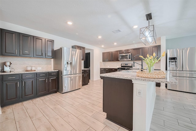 20864 Sheffield Park Dr, Porter, TX 77365 - kitchen with stainless steel appliances, backsplash, recessed lighting, light stone countertops, and hanging light fixtures
