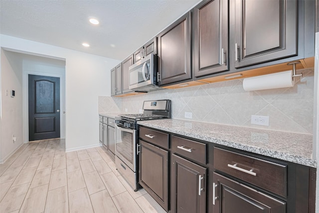 20864 Sheffield Park Dr, Porter, TX 77365 - kitchen with appliances with stainless steel finishes, backsplash, dark brown cabinetry, baseboards, and recessed lighting
