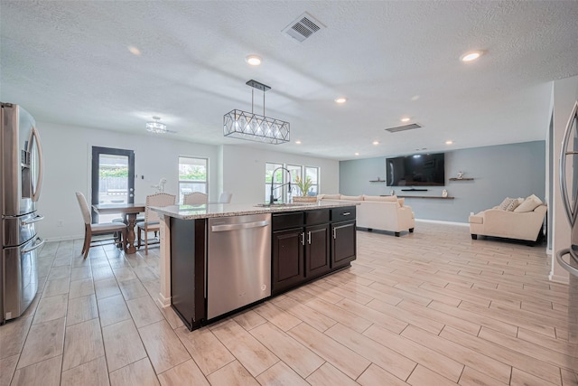 20864 Sheffield Park Dr, Porter, TX 77365 - kitchen featuring stainless steel appliances, a sink, open floor plan, a textured ceiling, and recessed lighting