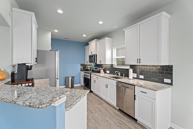 107 San Jacinto Dr, Baytown, TX 77523 - kitchen featuring appliances with stainless steel finishes, backsplash, white cabinets, light wood-style floors, and recessed lighting