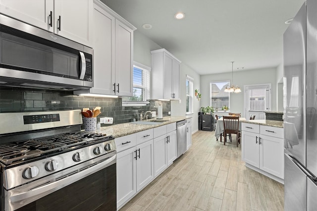 107 San Jacinto Dr, Baytown, TX 77523 - kitchen with appliances with stainless steel finishes, white cabinets, a chandelier, tasteful backsplash, and light wood-type flooring