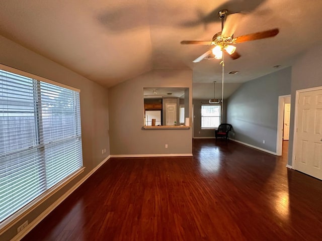 unfurnished living room featuring vaulted ceiling, dark wood-style floors, a ceiling fan, and baseboards