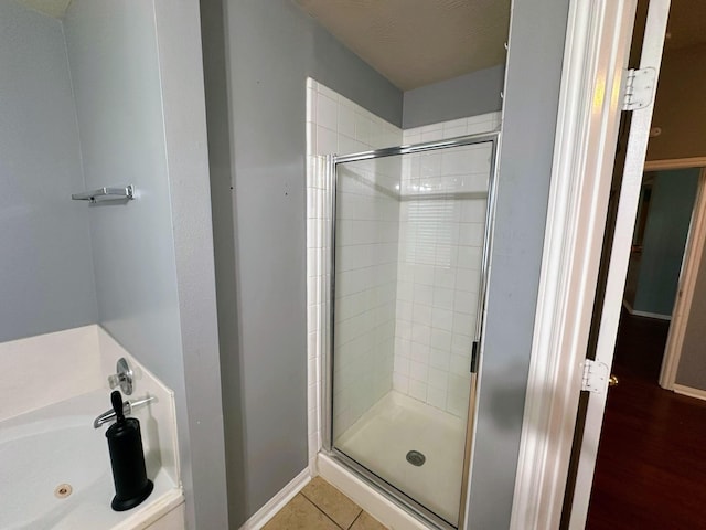 full bath with a stall shower, a jetted tub, and baseboards