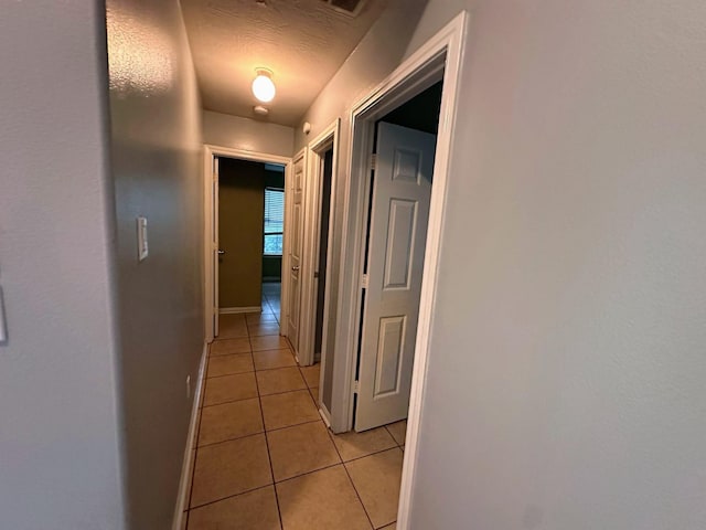 hallway featuring light tile patterned flooring and baseboards
