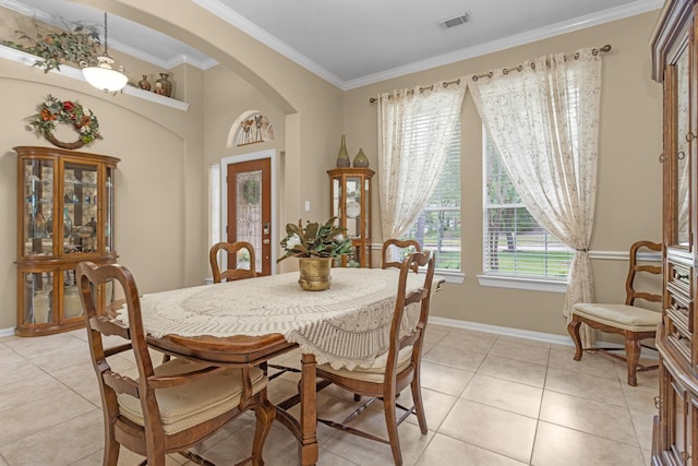 dining space featuring arched walkways, light tile patterned floors, crown molding, and baseboards
