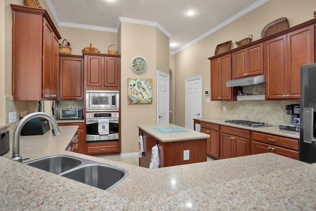 kitchen featuring stainless steel appliances, a sink, under cabinet range hood, crown molding, and tasteful backsplash