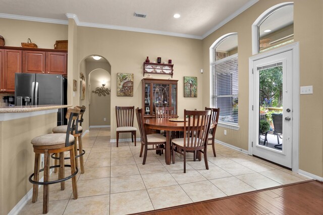 dining space featuring arched walkways, crown molding, baseboards, recessed lighting, and light tile patterned floors
