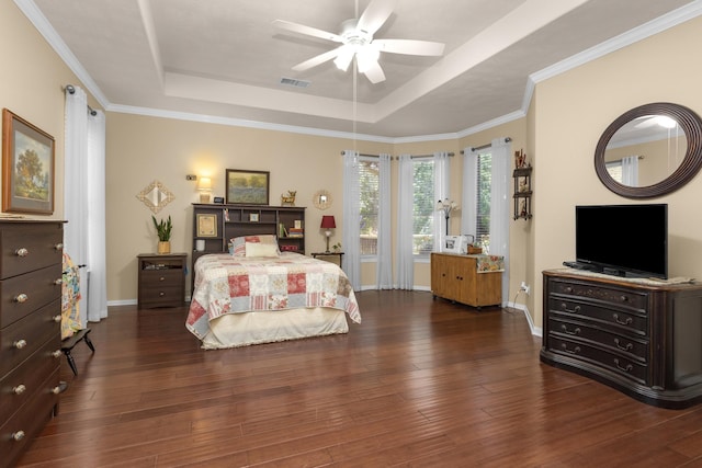 bedroom featuring a tray ceiling, wood finished floors, baseboards, and crown molding