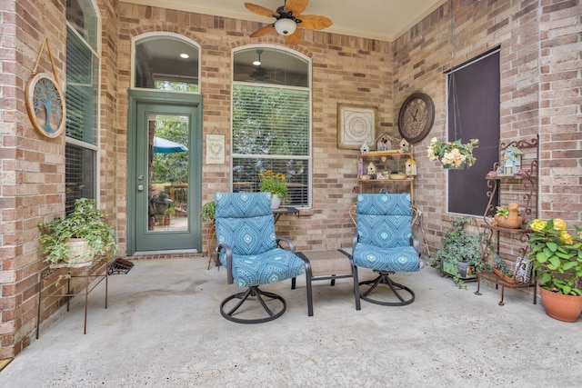view of exterior entry with a ceiling fan and brick siding