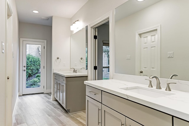 full bathroom featuring plenty of natural light, wood finished floors, two vanities, recessed lighting, and baseboards