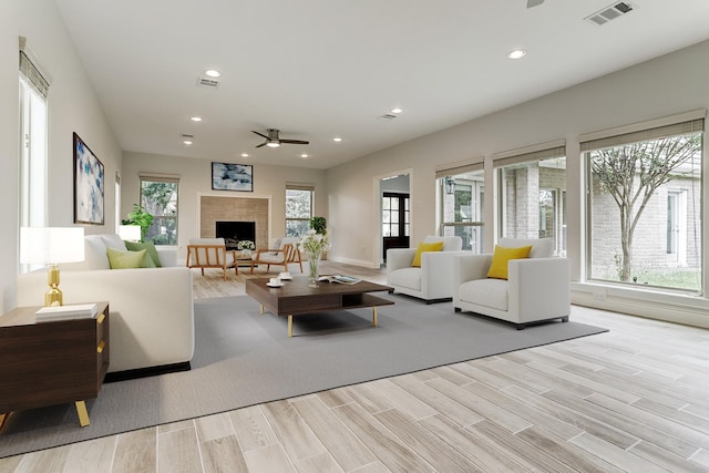 living room featuring a ceiling fan, a fireplace, healthy amount of natural light, wood finished floors, and recessed lighting