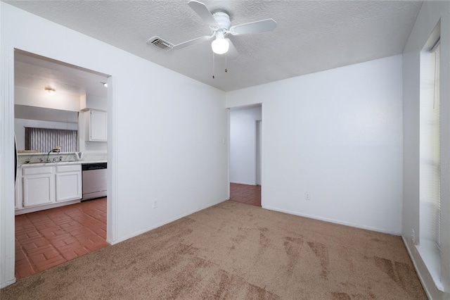 empty room featuring a ceiling fan, carpet floors, a sink, baseboards, and a textured ceiling