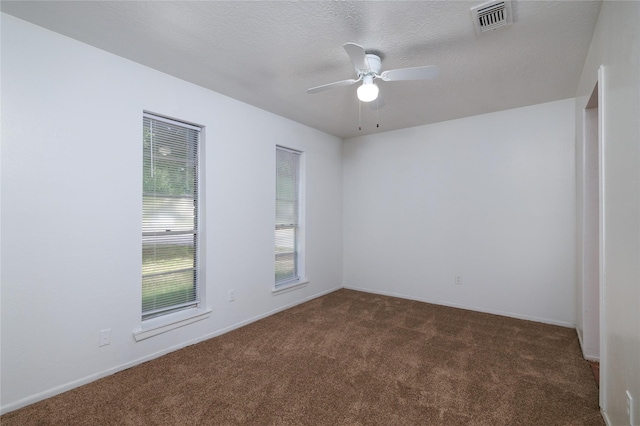 empty room with dark colored carpet, a ceiling fan, baseboards, and a textured ceiling