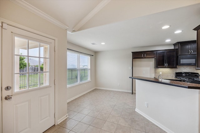 243 S Lantana Cir, Sealy, TX 77474 - kitchen featuring black microwave, stove, dark countertops, decorative backsplash, and light tile patterned floors