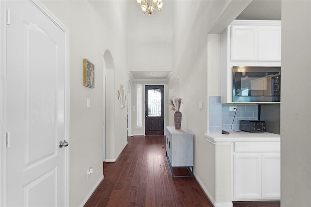 9615 Carson Ln, Iowa Colony, TX 77583 - corridor featuring baseboards, dark wood-style floors, arched walkways, a chandelier, and ornamental molding