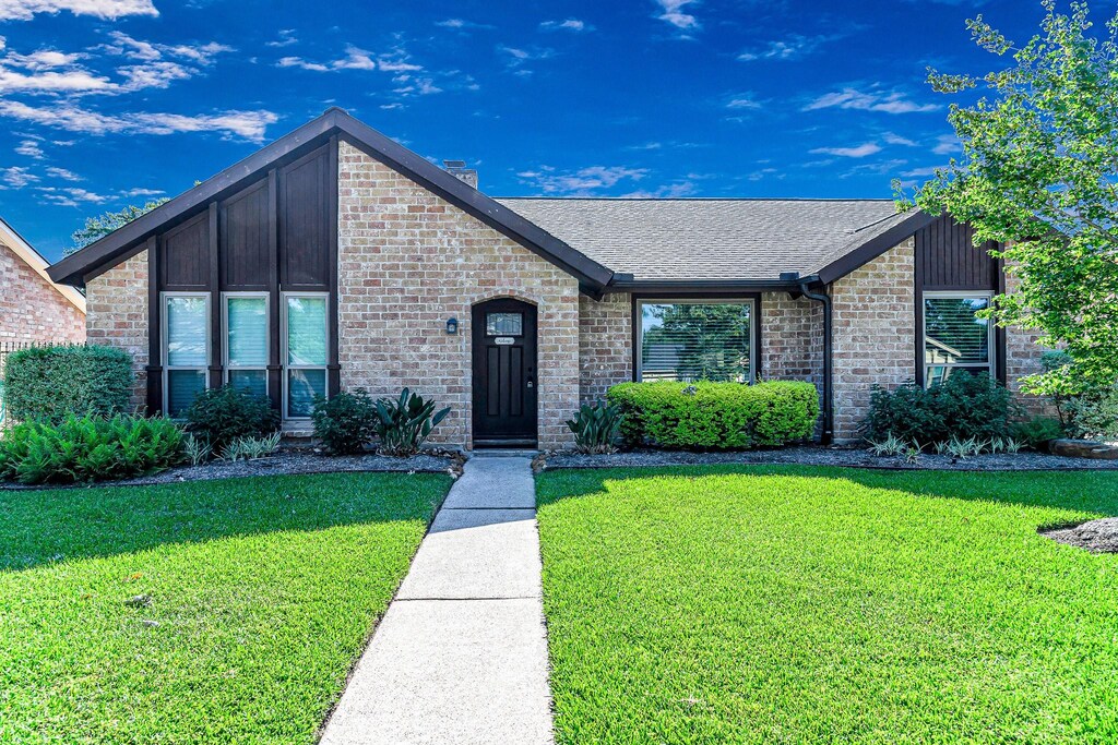 1223 Park Royale Ln, Katy, TX 77450 - mid-century inspired home featuring a front yard, a shingled roof, and brick siding