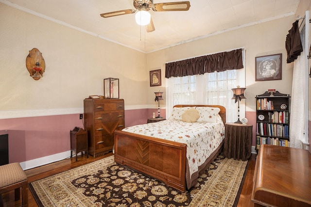 bedroom featuring wood finished floors, crown molding, a ceiling fan, and baseboards