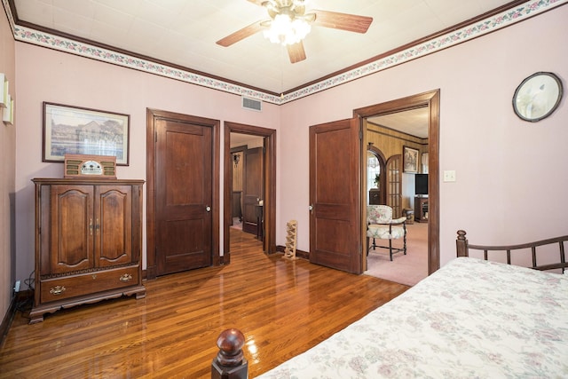 bedroom featuring dark wood finished floors, ceiling fan, crown molding, and baseboards