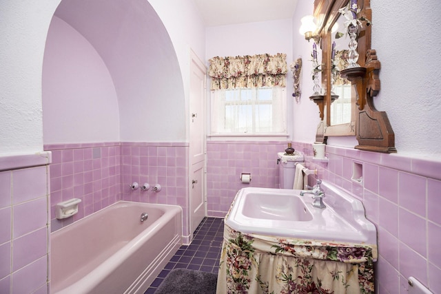 bathroom with tile patterned flooring, tile walls, a garden tub, a wainscoted wall, and vanity