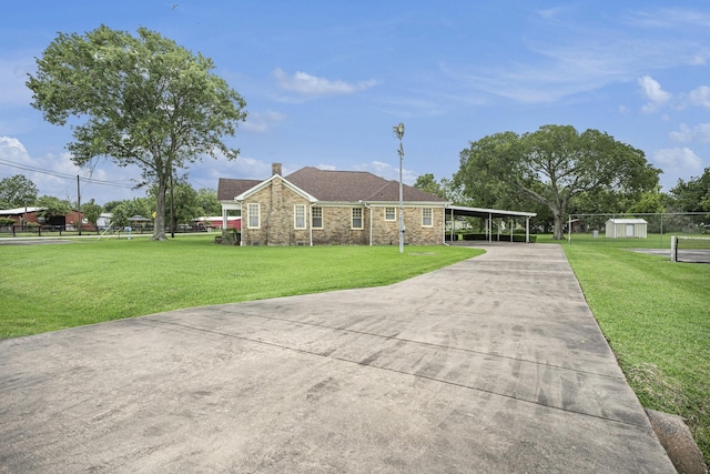single story home with driveway, a carport, and a storage unit
