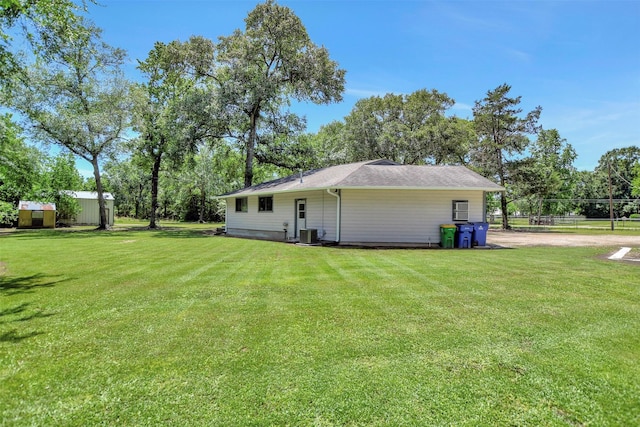 26410 Anderson Rd, Magnolia, TX 77354 - back of property with a yard, cooling unit, view of scattered trees, and an outbuilding