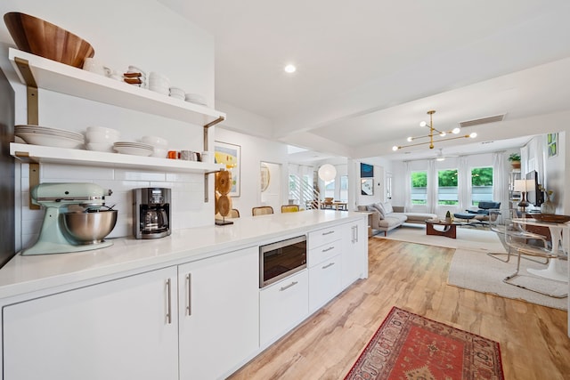 717 E 23rd St, Houston, TX 77008 - kitchen with open shelves, built in microwave, white cabinetry, light wood finished floors, and a peninsula