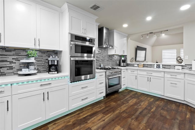 22022 Guston Hall Ln, Katy, TX 77449 - kitchen featuring wall chimney range hood, appliances with stainless steel finishes, light countertops, white cabinetry, and backsplash