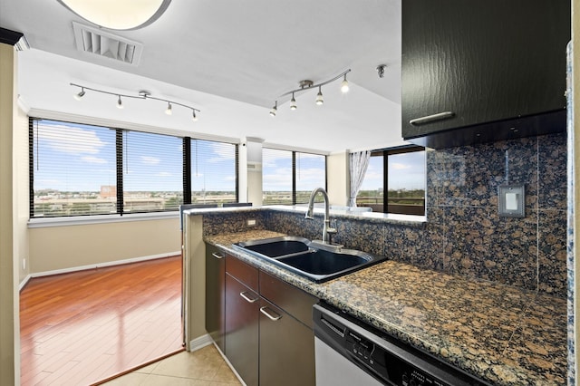 kitchen with a sink, dishwasher, baseboards, tasteful backsplash, and light wood-type flooring