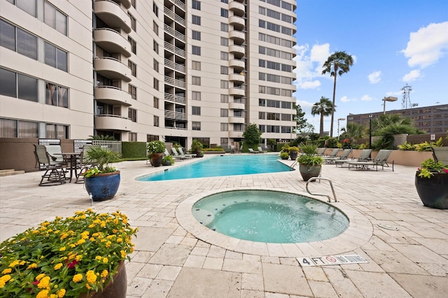 community pool with a community hot tub, a patio, and fence
