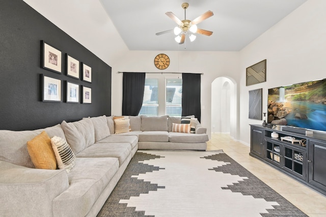living room with arched walkways, ceiling fan, vaulted ceiling, and light tile patterned floors