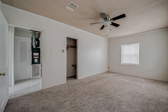 unfurnished bedroom featuring carpet floors, crown molding, ceiling fan, and a closet