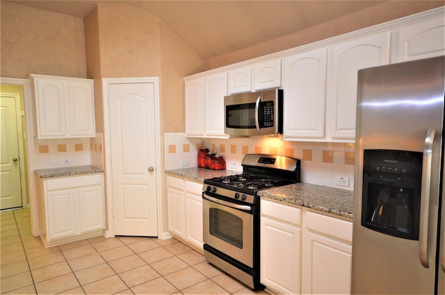 kitchen with stainless steel appliances, vaulted ceiling, light tile patterned floors, decorative backsplash, and light stone countertops